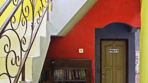 A staircase with a metal railing leading to a room with a wooden door labeled "TOILET".