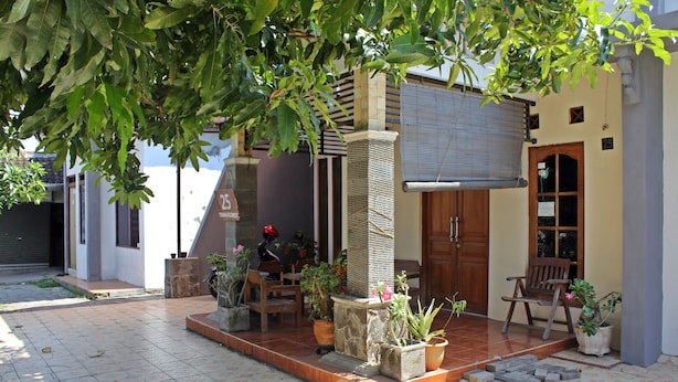 A small, modern house with a tiled patio, a stone pillar, and several potted plants.