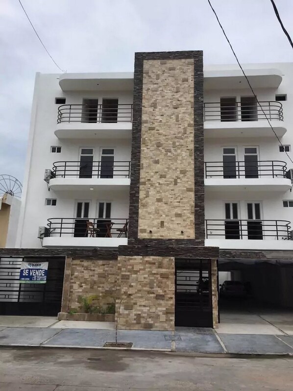 A multi-story building with a central vertical section of stone and metal.