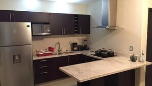 A modern kitchen with dark cabinets, stainless steel appliances, and a marble countertop.