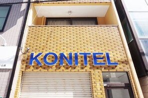 A building with a yellow brick facade and a large blue sign that reads "KONITEL".