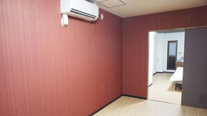 Een kamer met rode wanden, een houten vloer en een witte airconditioning die aan de muur hangt.