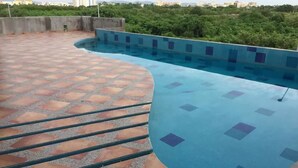 A rooftop swimming pool with a curved design, surrounded by a patterned tiled deck. - Depa Torre Marina (Mazatlán)