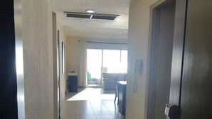 A hallway with tiled flooring leading to a living area with a sofa and a table. - Condominio Malecon (Mazatlán)