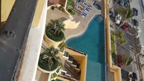A resort with a central pool, lounge chairs, and palm trees. - Condominio Malecon (Mazatlán)