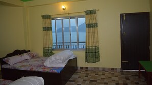 A bedroom with a bed, a window with curtains, a door, and a view of mountains. - 360 Lakefront Restro and Lodge (Pokhara)