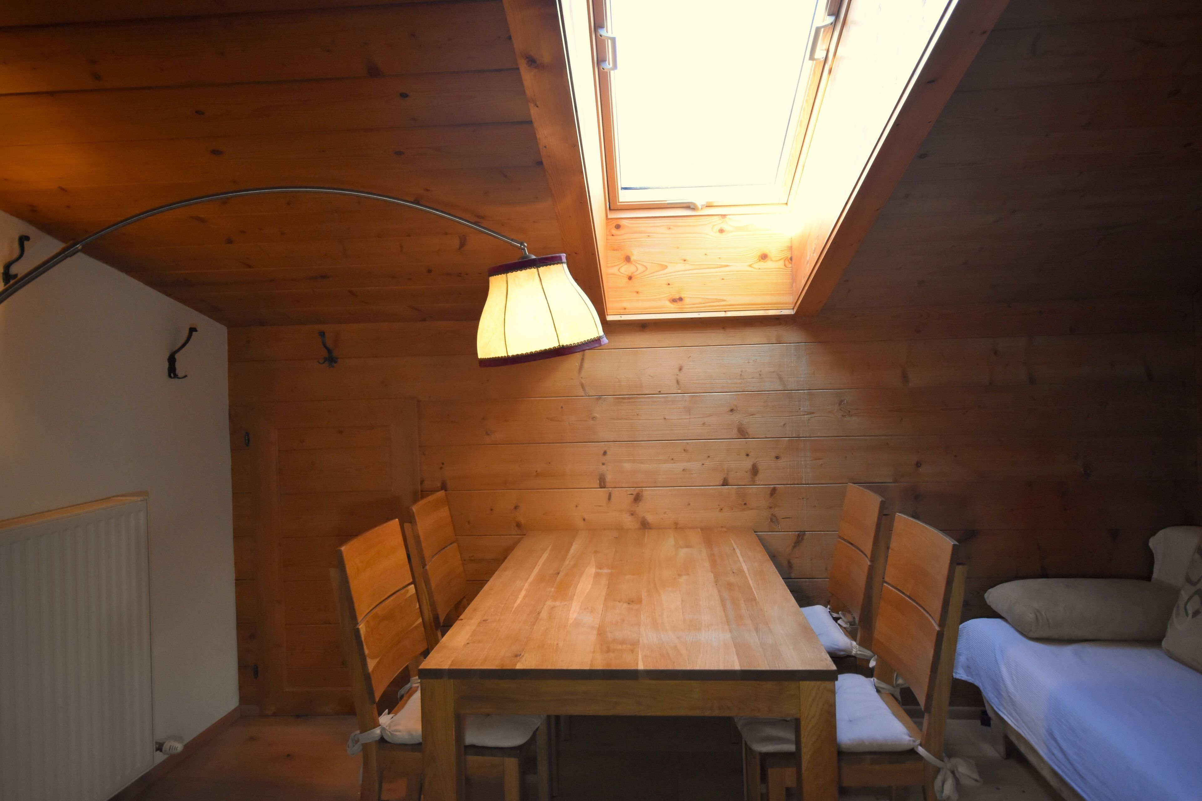Ein Holzinnenraum mit Oberlicht, Tisch, Stühlen und einem Bett.