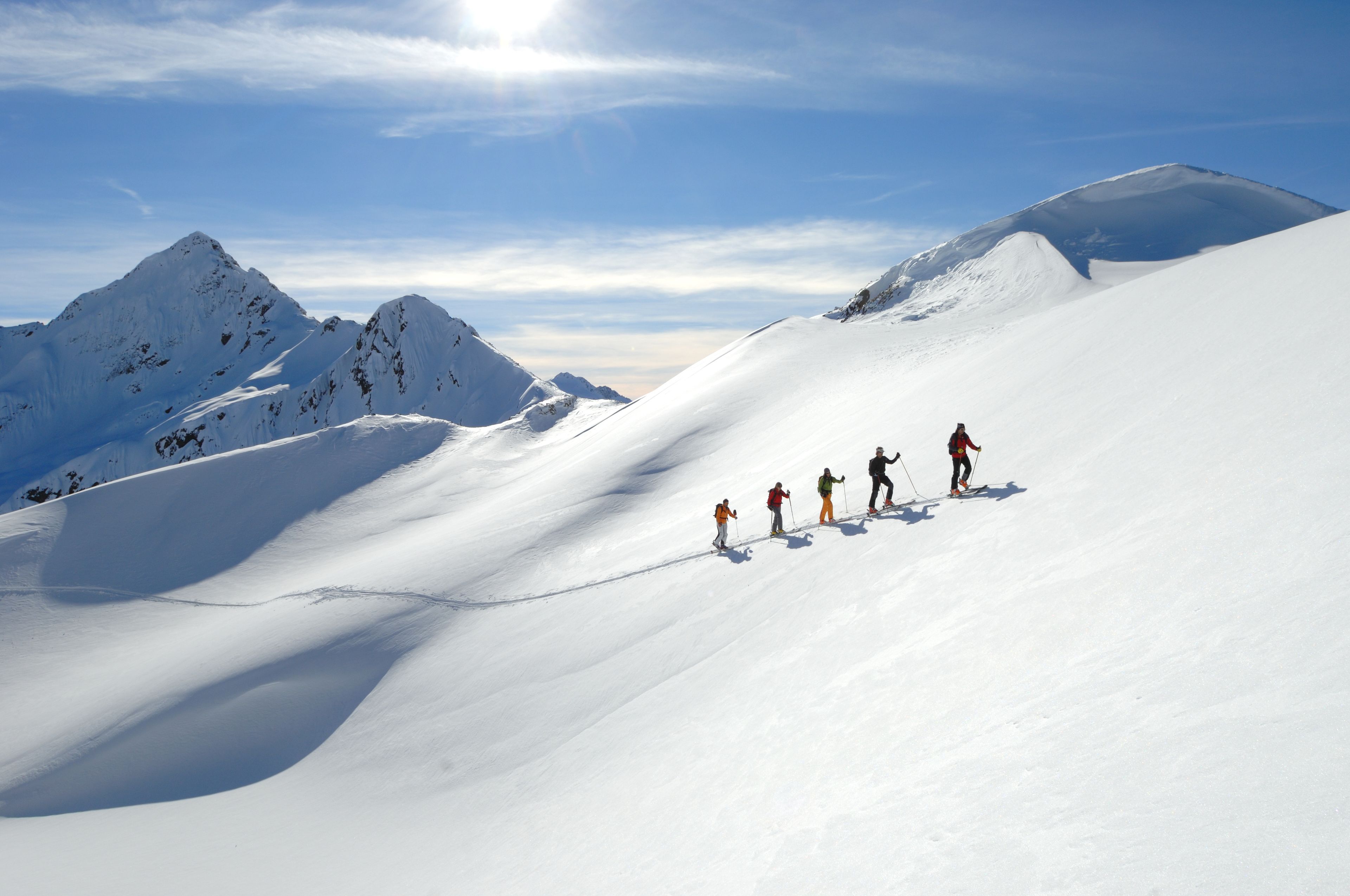 A group of skiers on a snowy mountain slope with clear skies.