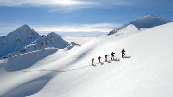 A group of skiers on a snowy mountain slope with clear skies.