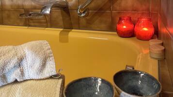 Un baño con bañera, dos lavabos, una toalla y dos velas rojas.
