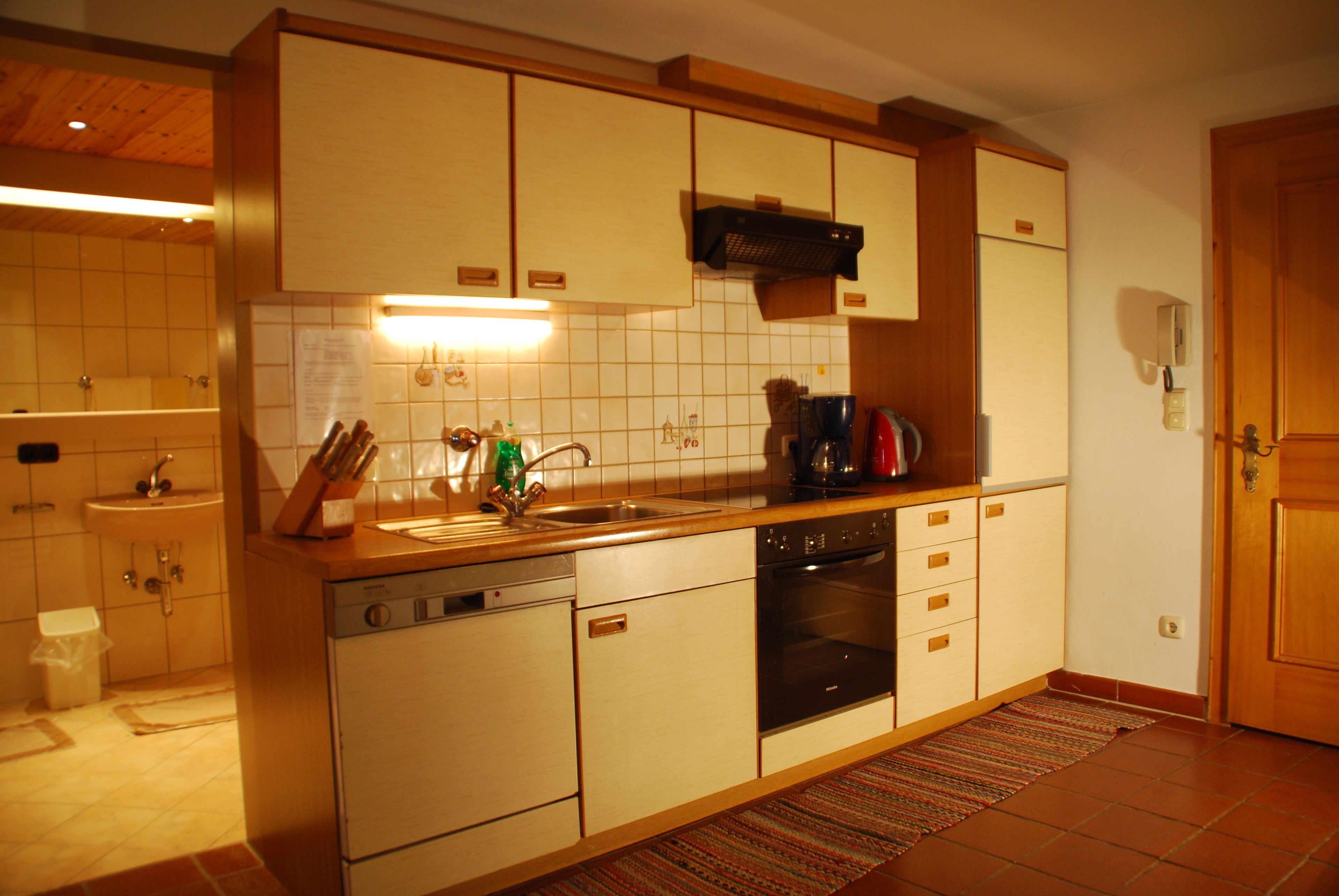 A kitchen with wooden cabinets, a dishwasher, an oven, and a sink.