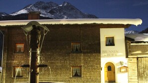 A rustic building with a wooden facade, a sign reading "BRUNNEN HOF," and a snow-covered mountain in the background. - Brunnenhof (Pettneu am Arlberg)