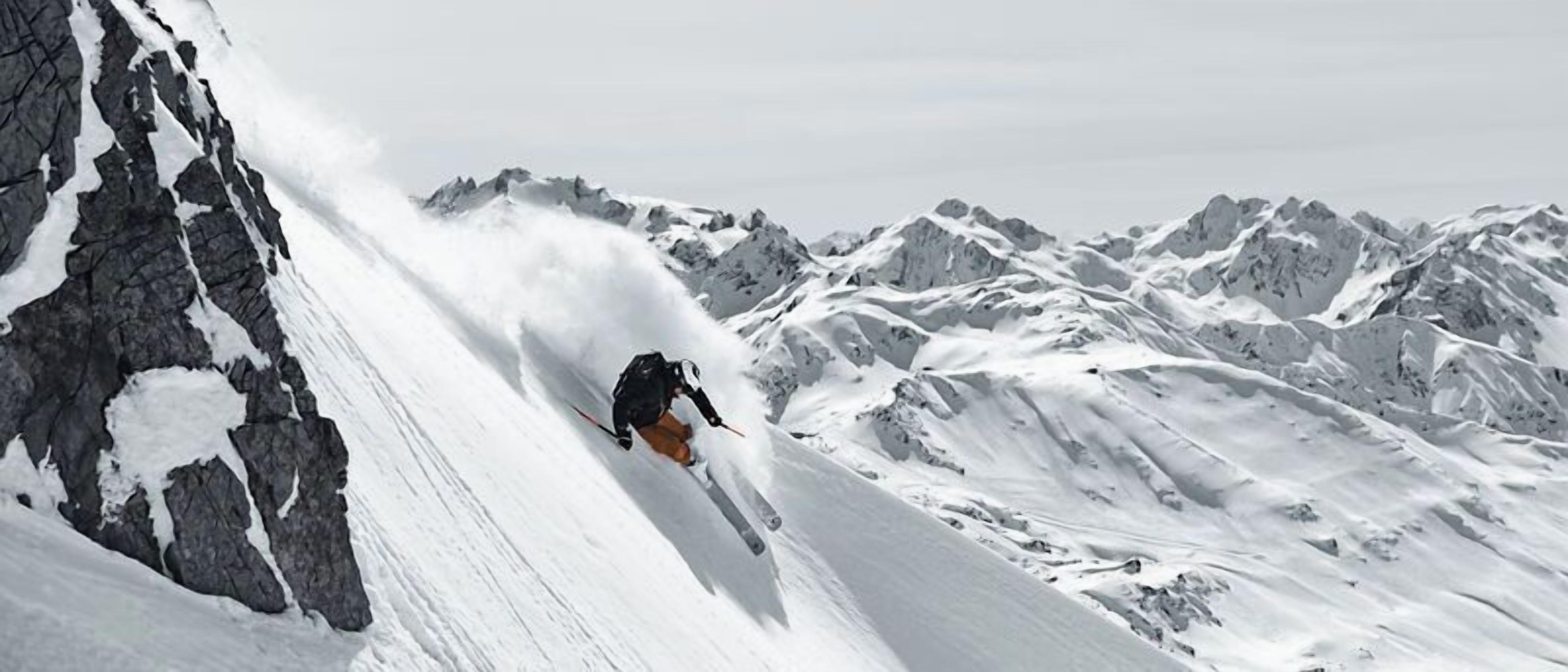 Een persoon skiënd op een steile, met sneeuw bedekte berghelling.