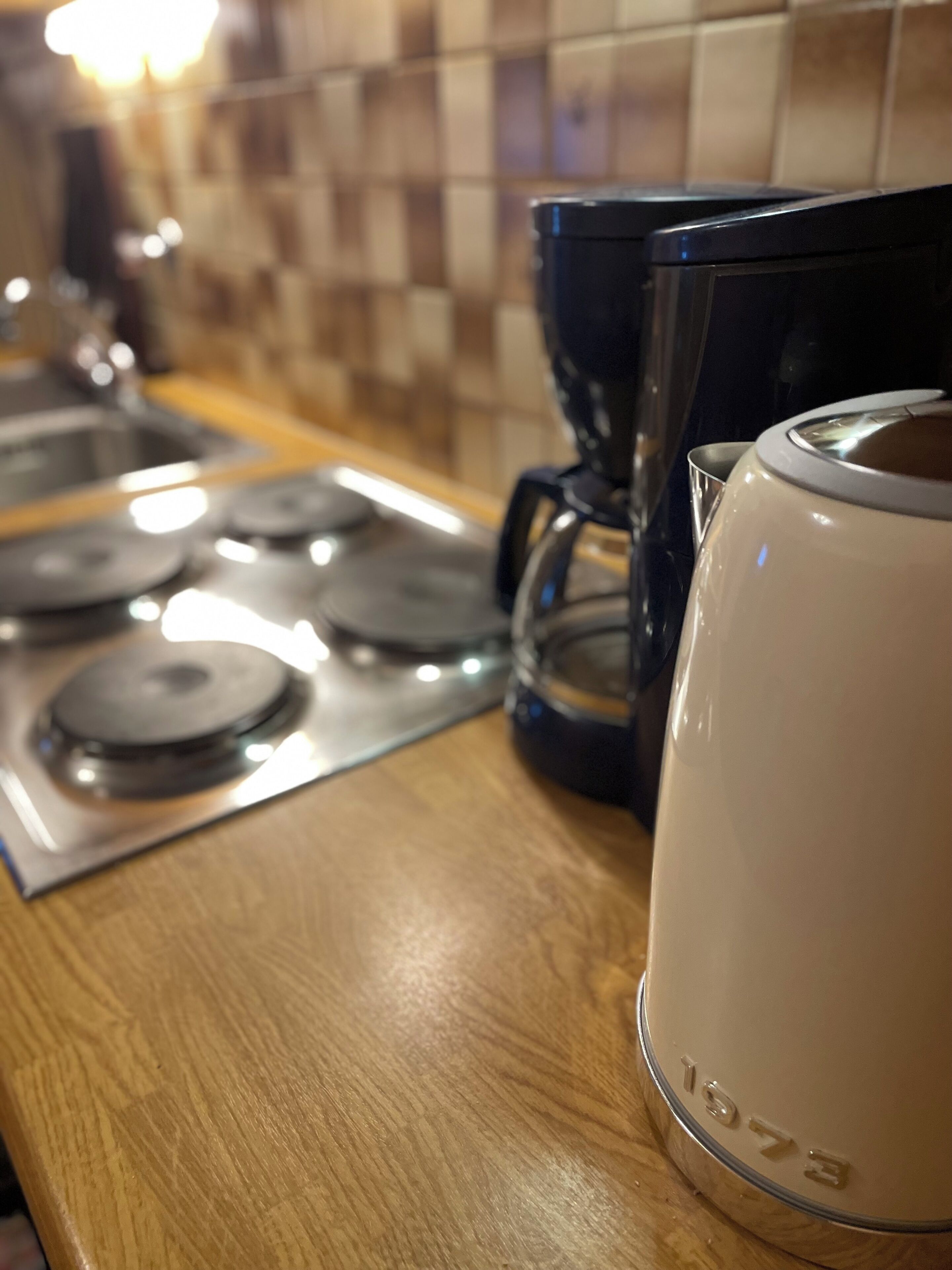 Una cucina con una macchina da caffè, un bollitore e un fornello.