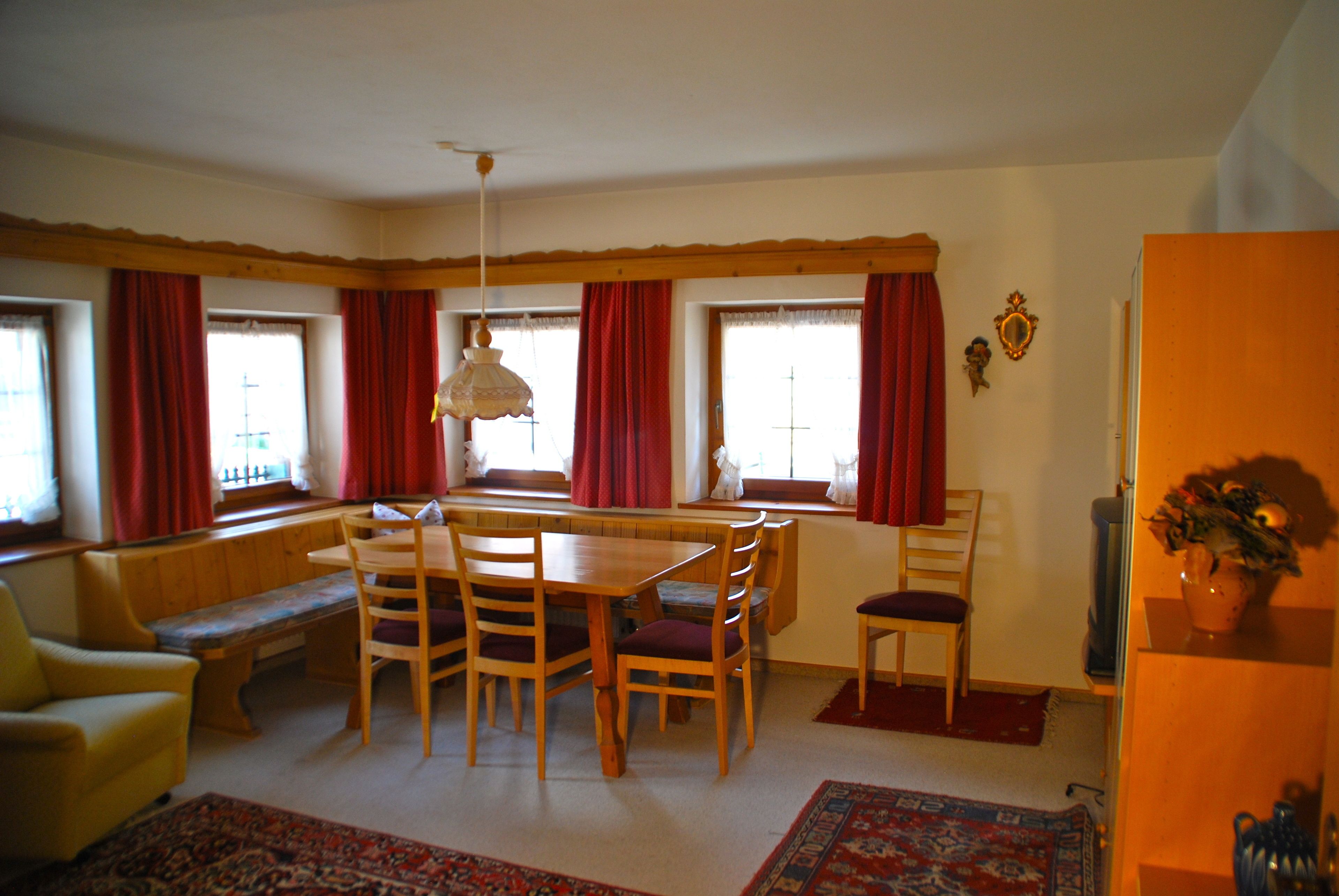 A dining area with a wooden table and chairs, a bench, and a window seat.