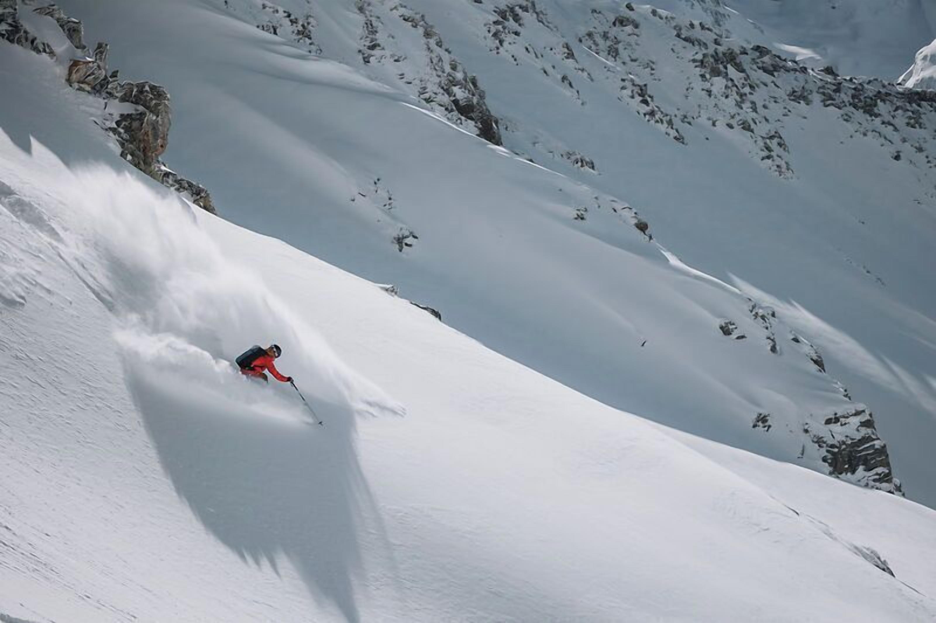 A skier descending a snow-covered slope with rocky outcrops.