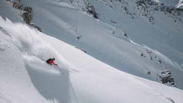 A skier descending a snow-covered slope with rocky outcrops.