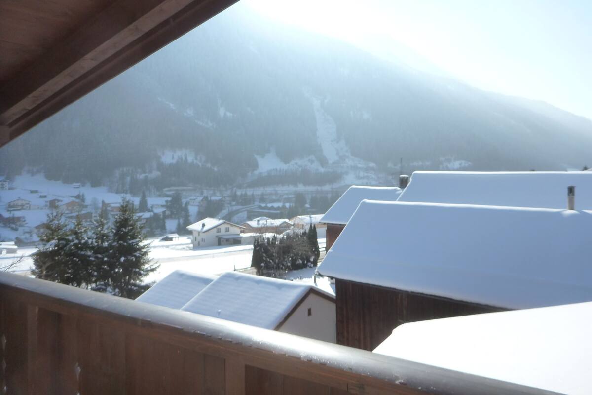 A snowy mountain landscape with houses and a wooden structure.