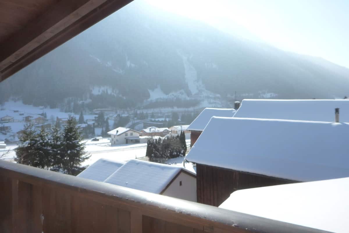 A snowy mountain landscape with houses and a wooden balcony.