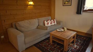 Una sala de estar acogedora con un sofá, una mesa de centro de madera y una alfombra estampada.