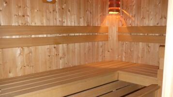 A wooden sauna with benches and a visible temperature gauge.