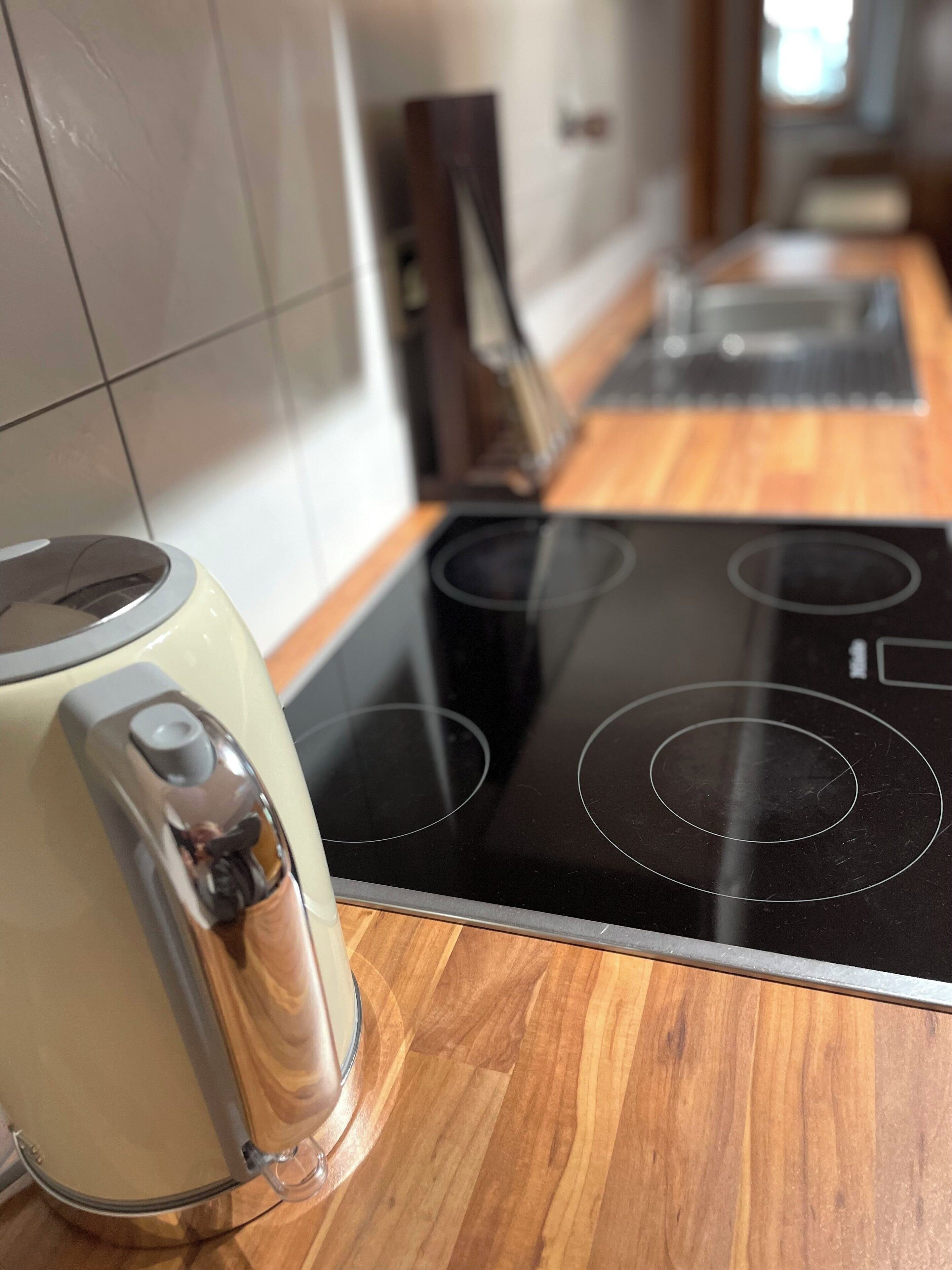 Una cocina con estufa moderna y hervidor.