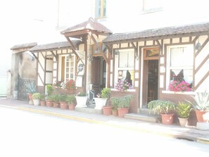 A building with a traditional architectural style, featuring a wooden facade and multiple windows. There are potted plants arranged along the front, and a sign indicating a restaurant or cafe. - Auberge des Voyageurs (Saint-Germain-Laval)