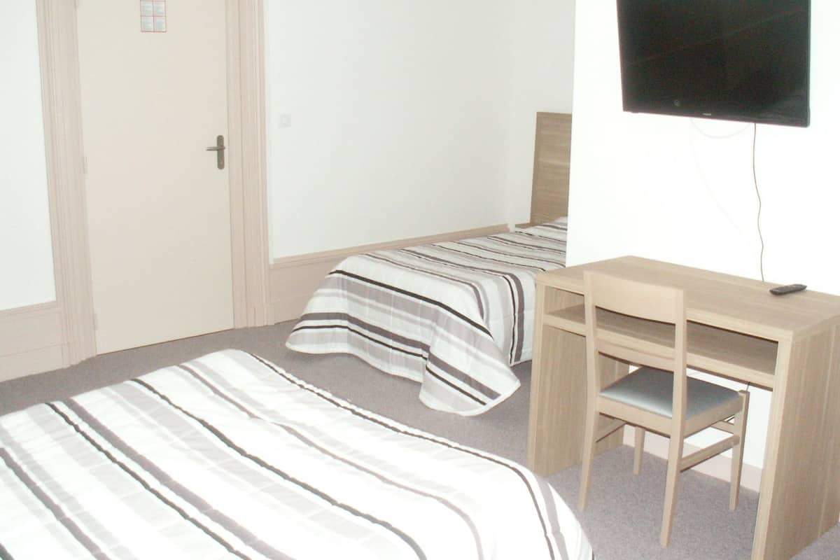 Une chambre avec deux lits, un bureau et une télévision.