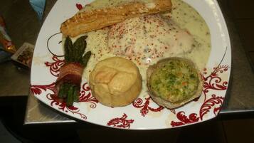 Un plato con diversos alimentos, entre ellos un pastel enrollado, salsa cremosa, un producto horneado y salsa verde.