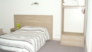 Een slaapkamer met een bed, nachtkastje, kledingkast en spiegel.