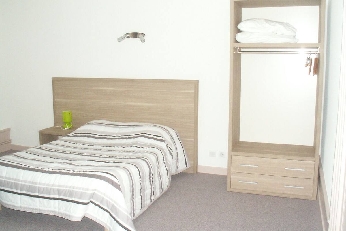 Une chambre à coucher comprenant un lit, une table de chevet, une commode, une armoire et un miroir.