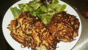 Een bord met twee aardappelpannenkoeken en een salade.