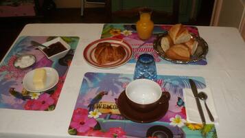 A table set with breakfast items including croissants, bread, butter, jam, and a cup of coffee.