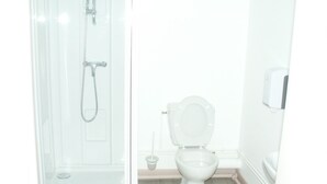 Een badkamer met douche, toilet en handdroger.
