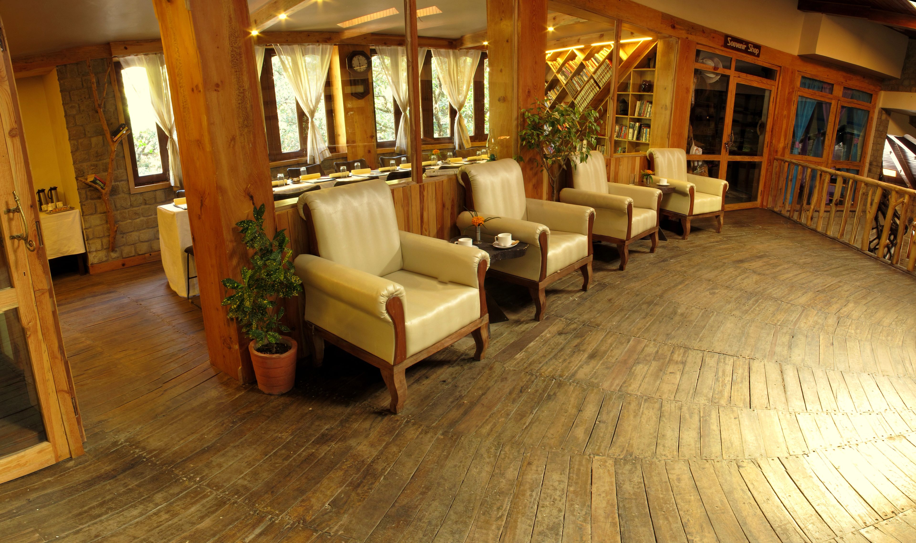 A cozy interior with wooden floors, leather armchairs, and a bookshelf.