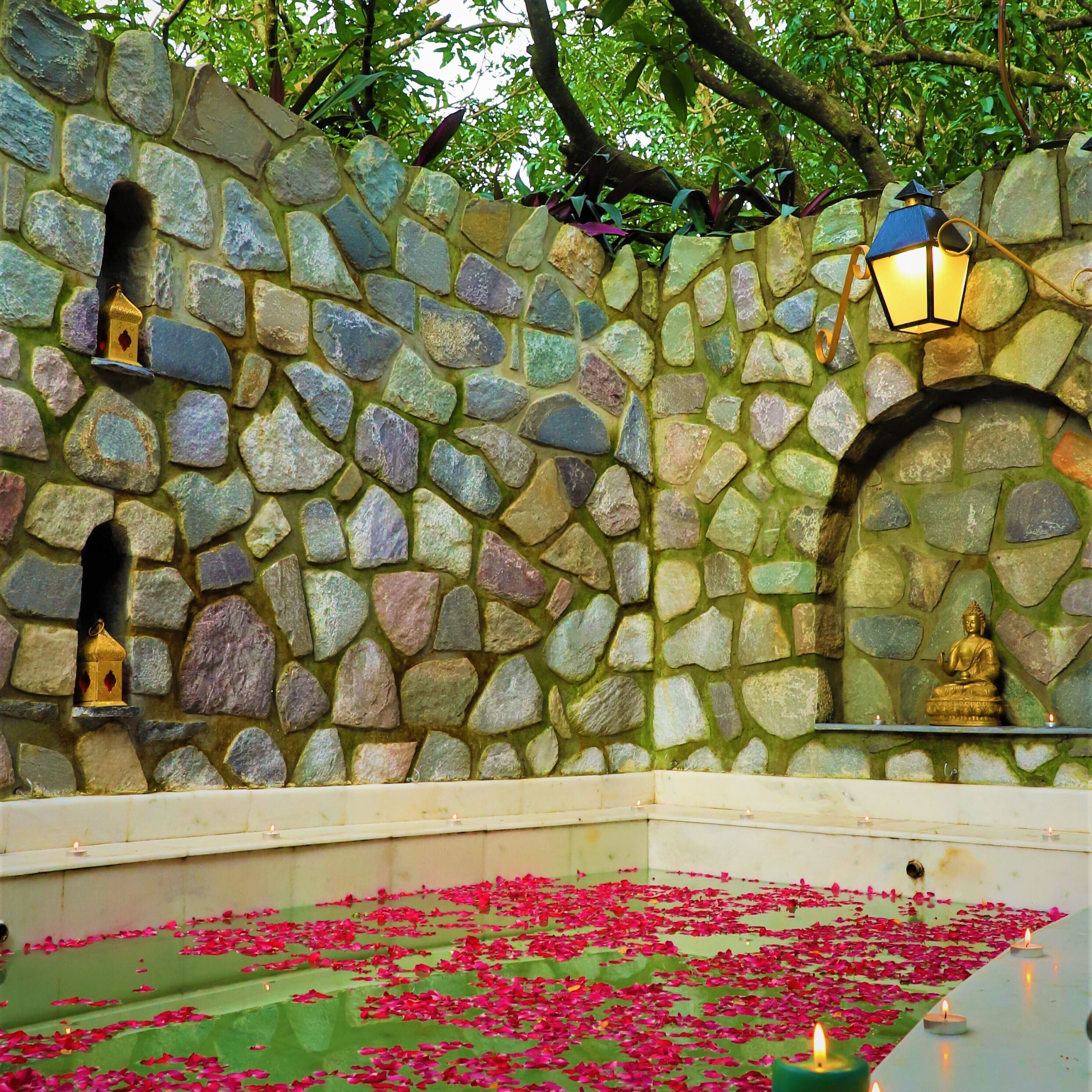 A stone wall with a Buddha statue, a lantern, and a small shrine.