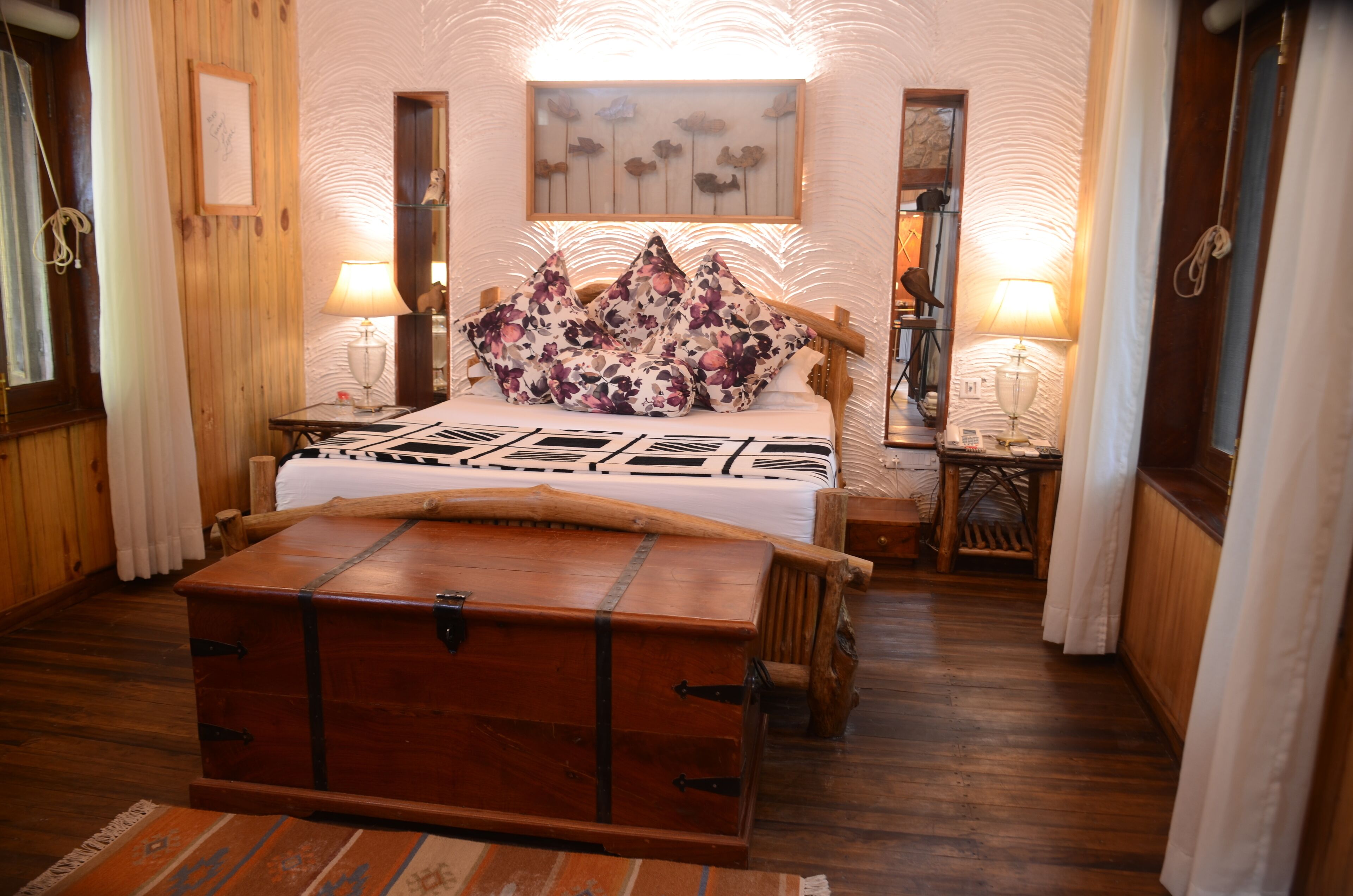 A wooden themed room with a bed, a wooden chest, and a mirror on the wall.
