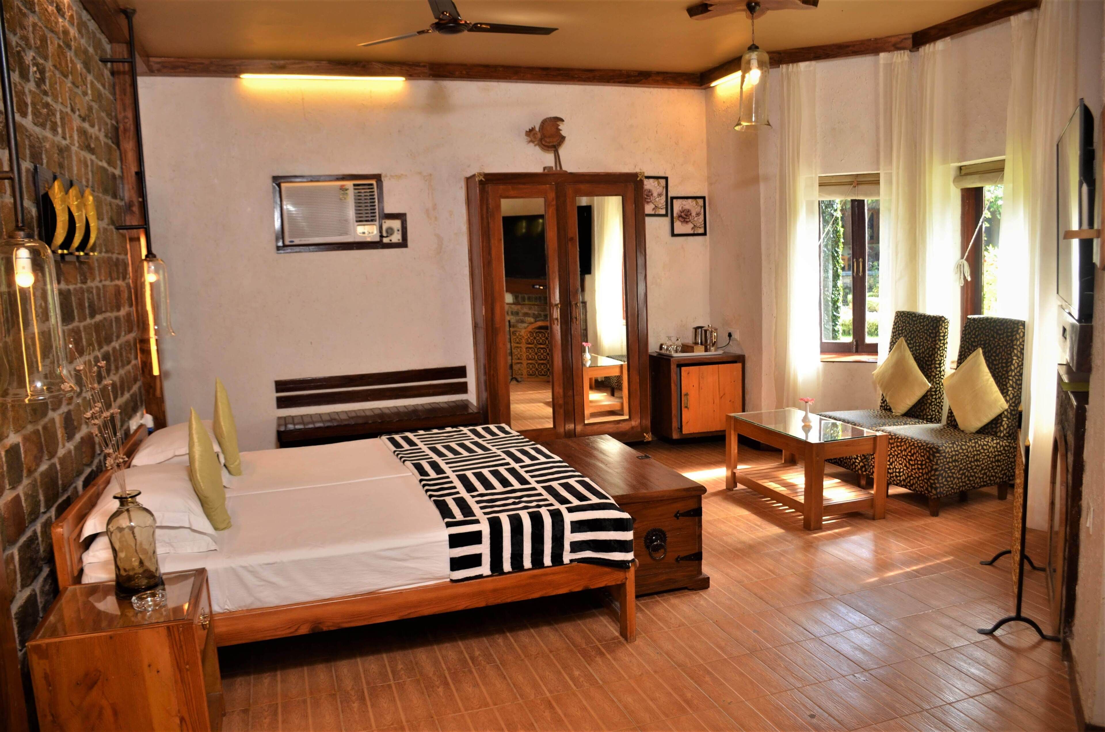 A bedroom with a wooden bed, a wooden nightstand, a bedside table, a chair, a desk, and a window with curtains.