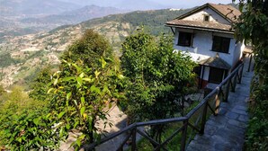 Un edificio tradicional con techo inclinado, rodeado de abundante vegetación y campos escalonados.