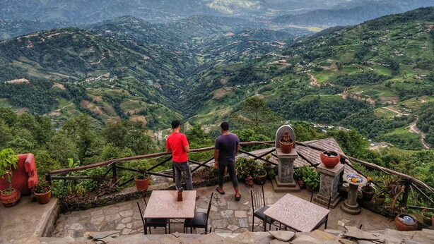 Una terraza con mesas y sillas con vistas a un paisaje montañoso.