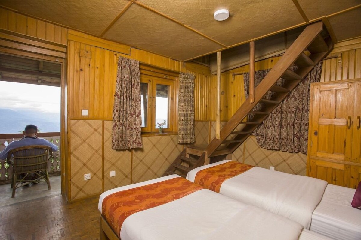 A wooden cabin with two beds, a staircase, and a view of the outdoors.
