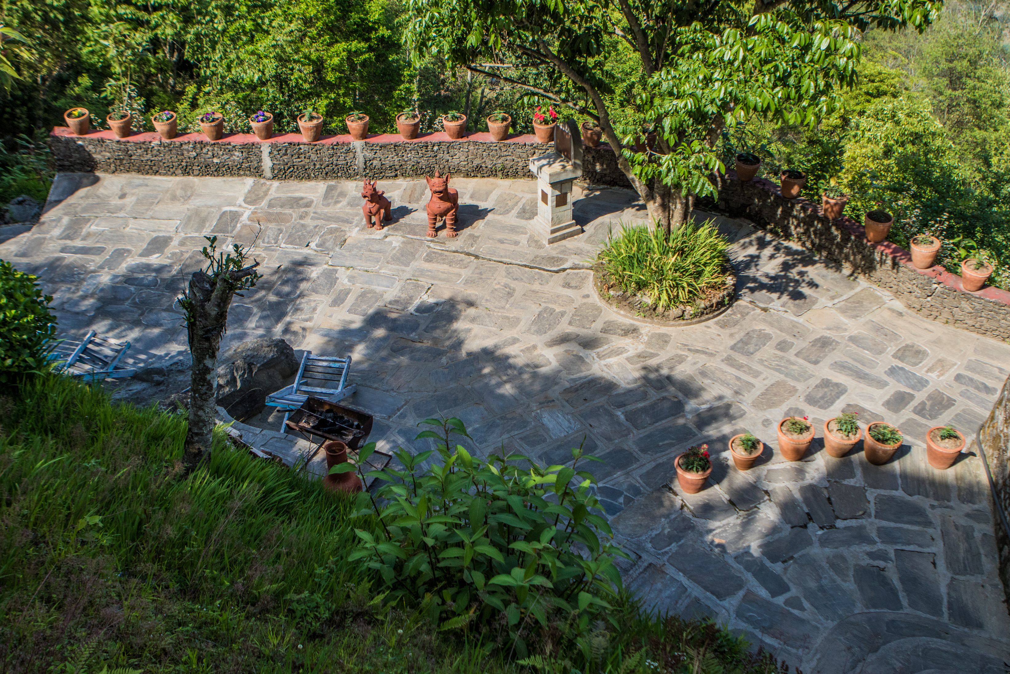 A stone patio with potted plants and a statue.