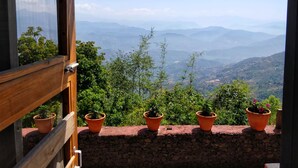 Una habitación con vistas a campos en terrazas y montañas distantes.