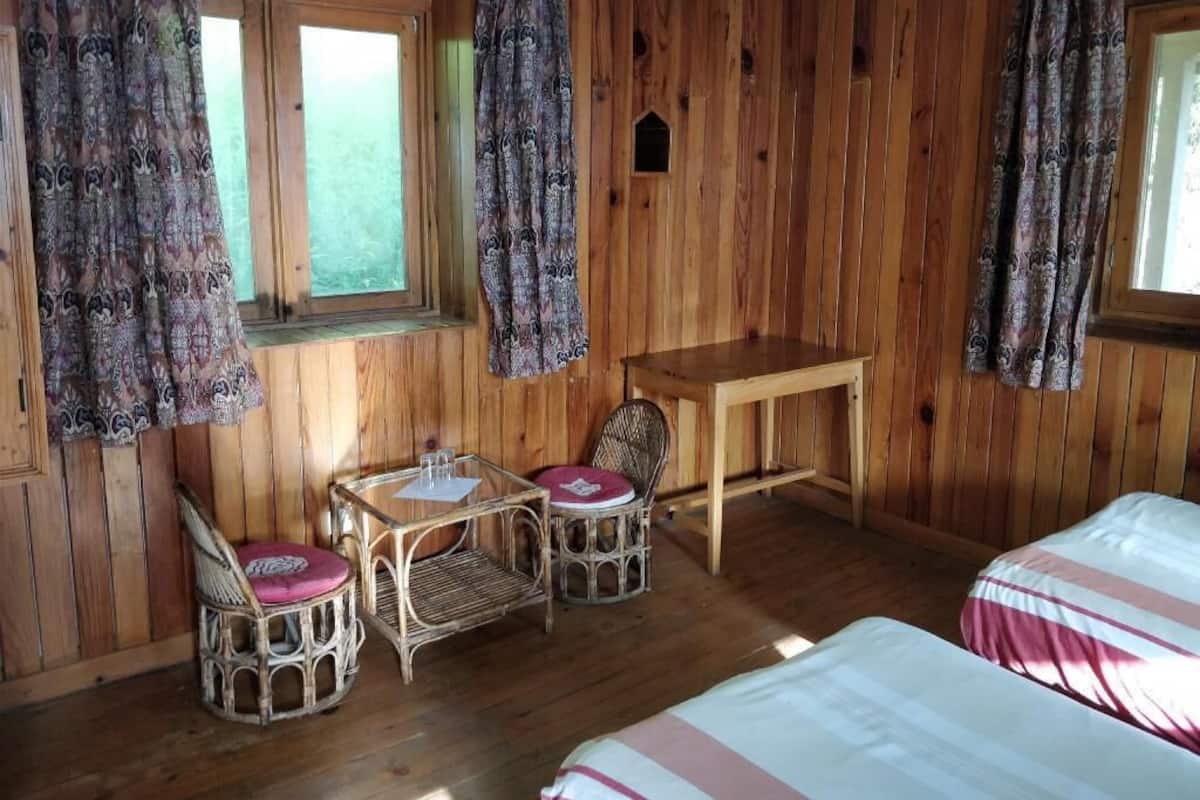 Una habitación de madera con dos camas, una mesa y sillas, y cortinas.
