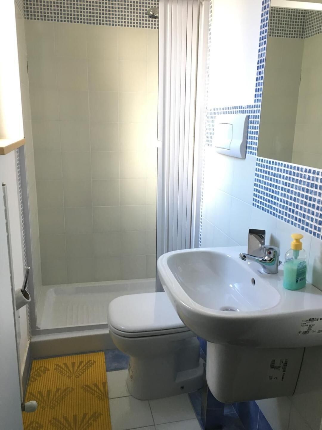 Un baño con ducha, inodoro, lavamanos y espejo.