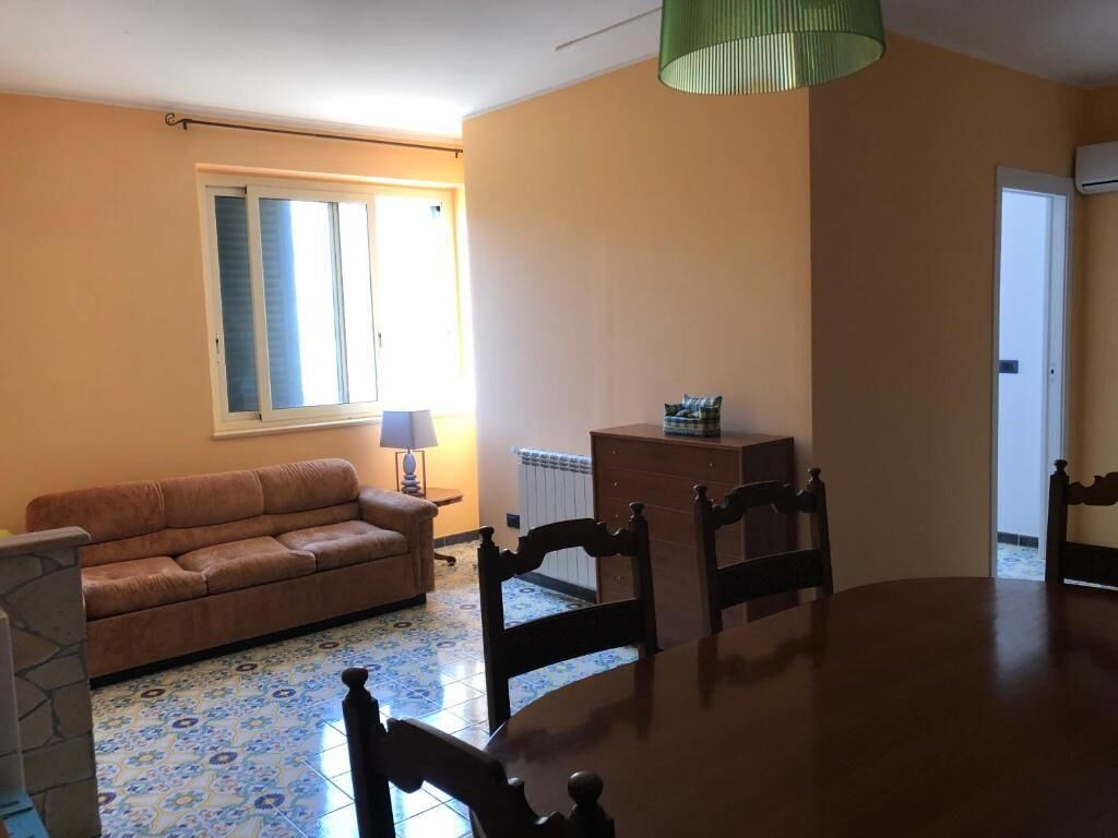 Un salon comprenant un canapé, une table à manger, des chaises, une lampe et un radiateur.