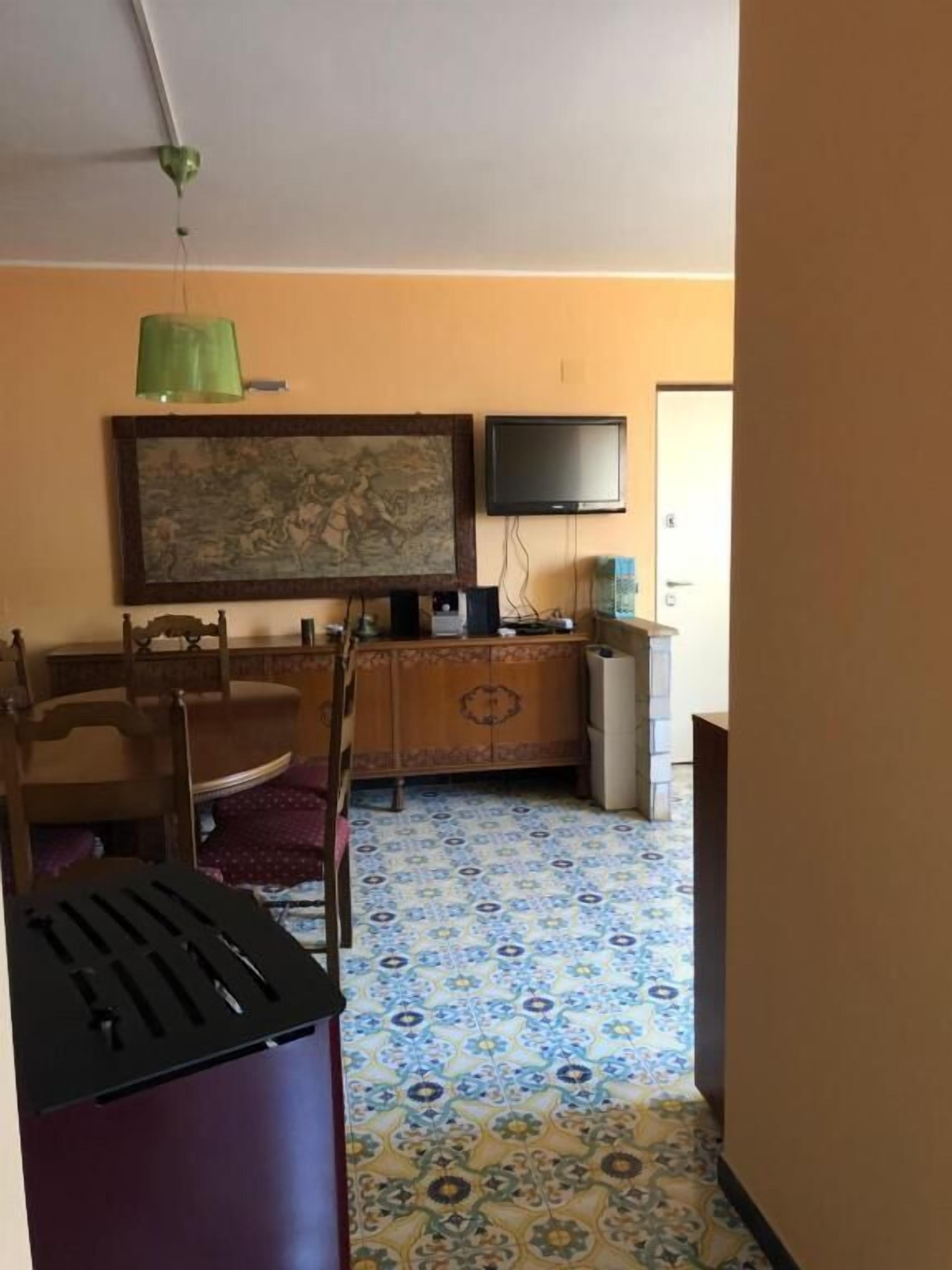 A room with a dining table, chairs, a television, and a patterned floor.
