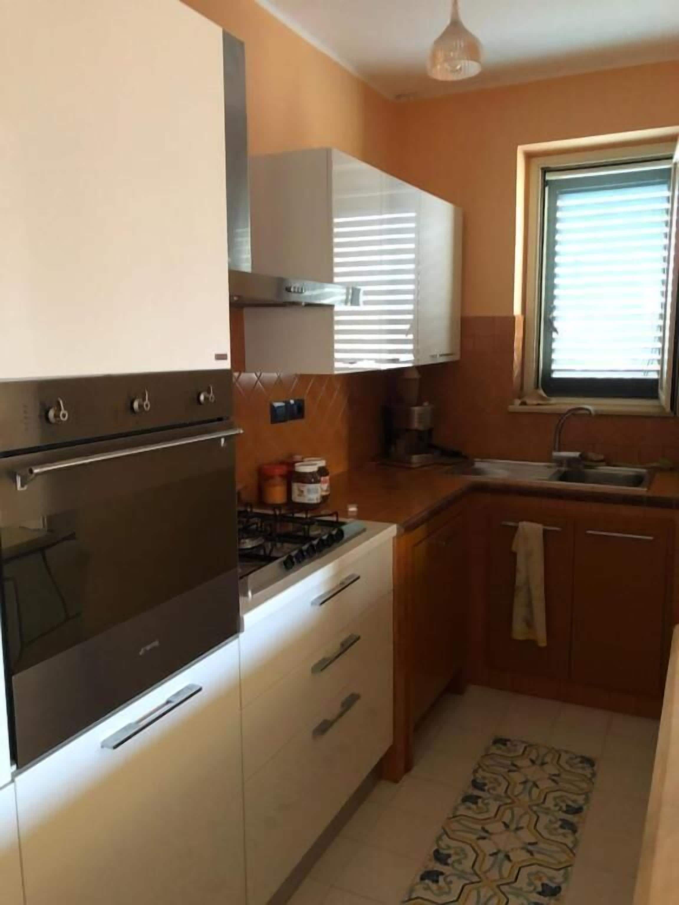 Una cucina compatta con piano cottura, forno e pensili.