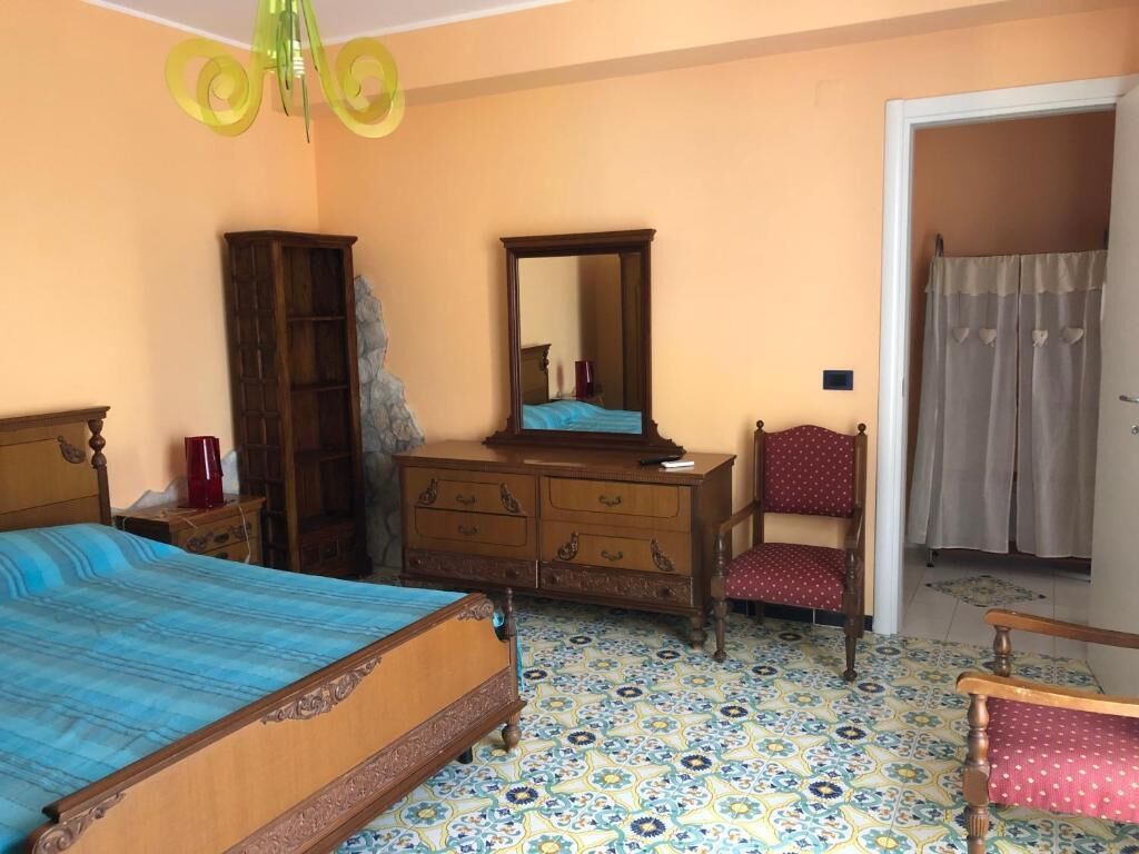 A bedroom with a bed, dresser, chair, and a mirror.