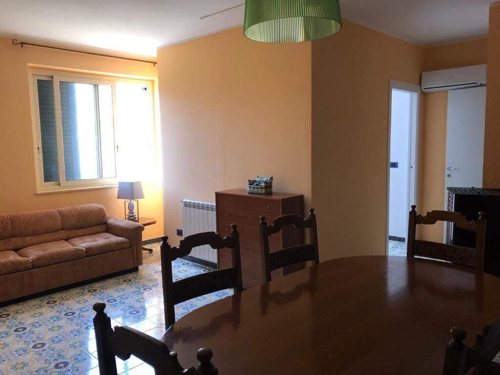 Una sala de estar con sofá, mesa de comedor, sillas, lámpara y radiador.